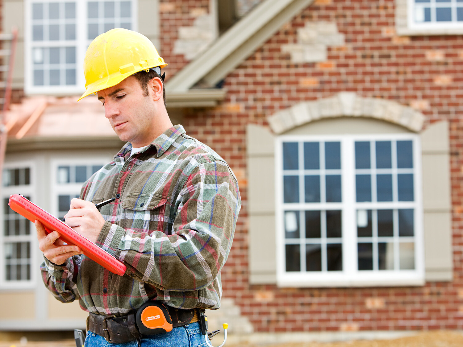 contractor making notes in front of new home