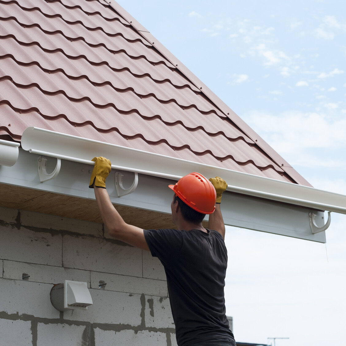 worker installs the gutter system on the roof commercial property drainage