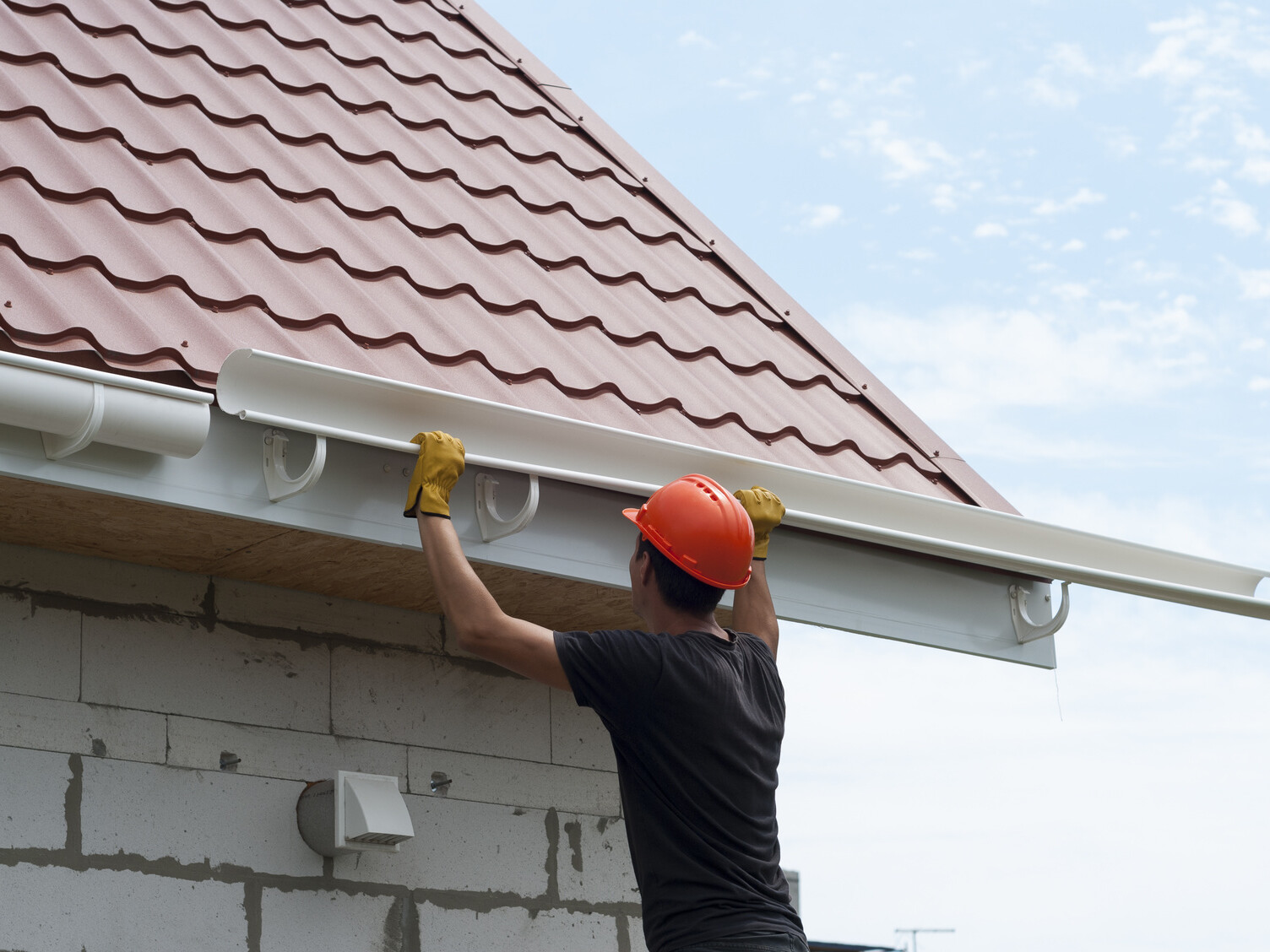 worker installs the gutter system on the roof commercial property drainage