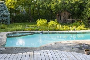Backyard with outdoor in ground pool, garden, deck and stone patio mikula