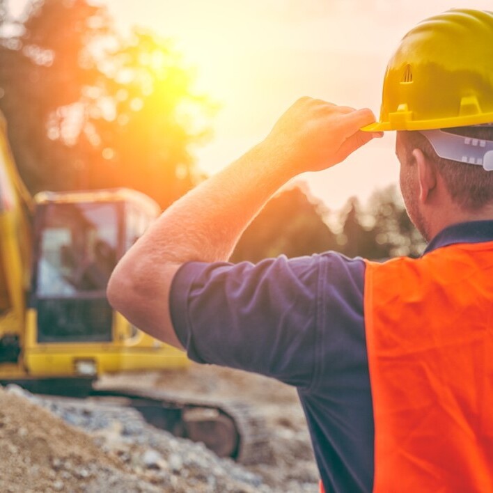 excavation worker holding hardhat at jobsite