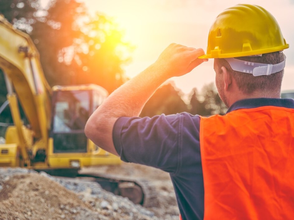 excavation worker holding hardhat at jobsite