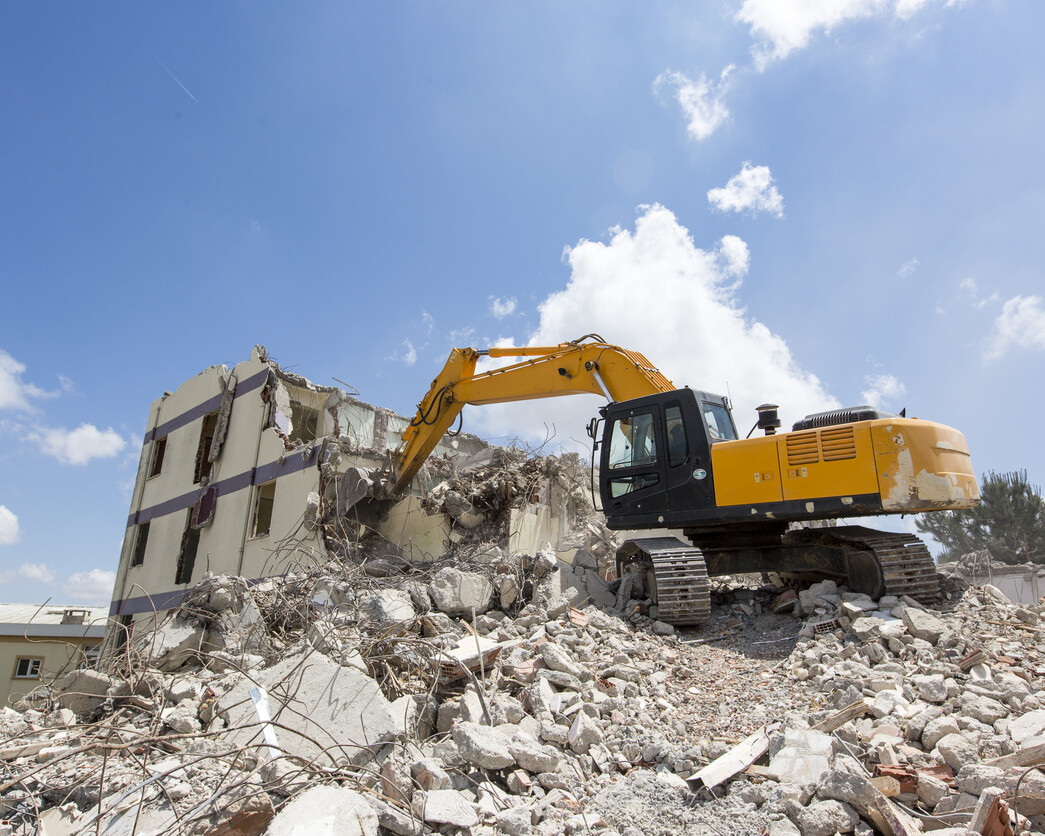 Excavator demolishing building