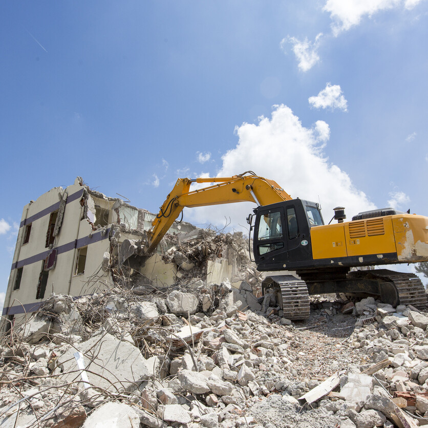 Excavator demolishing building