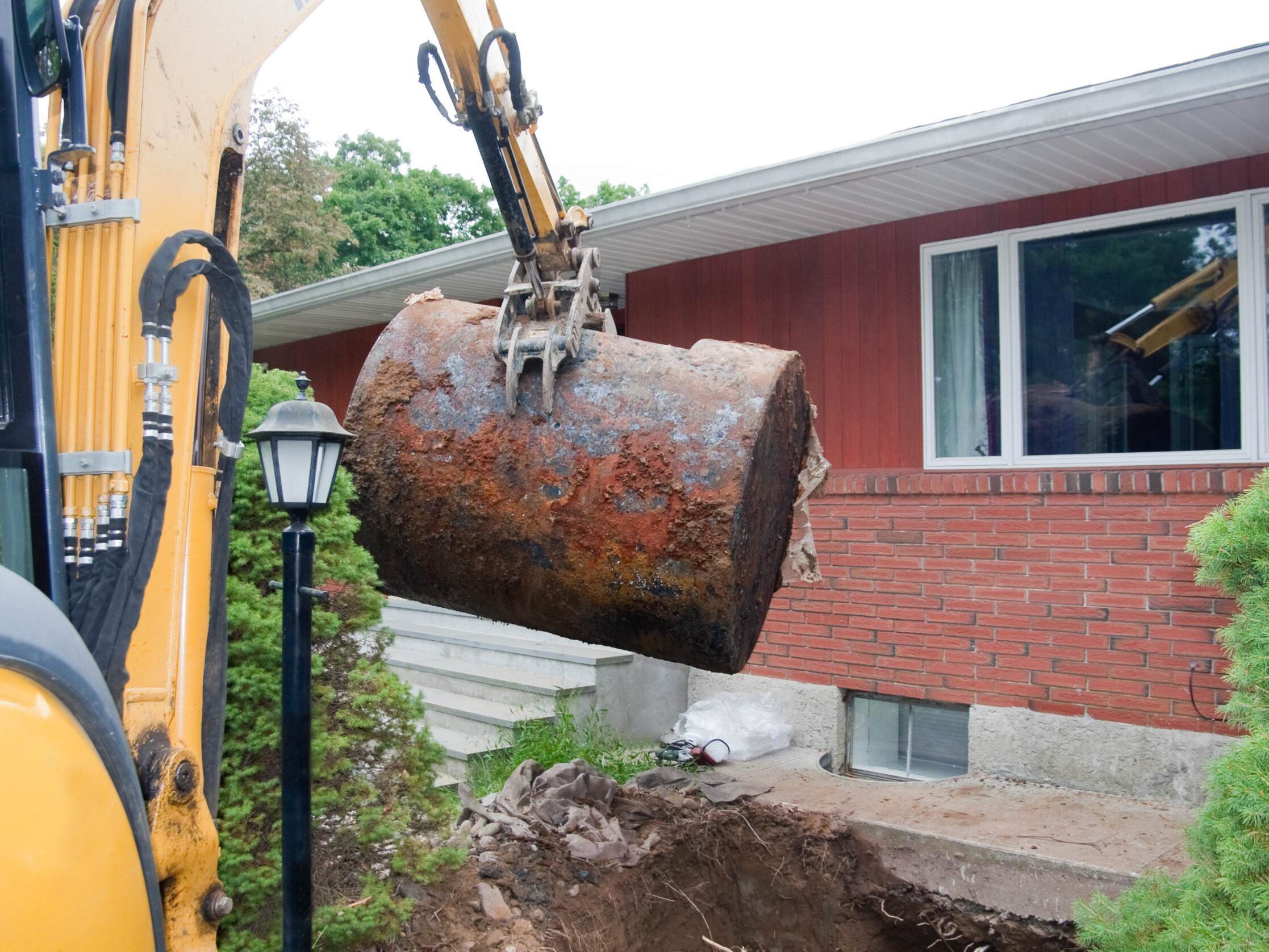 An underground oil tank is dug up and removed by a contracting company.