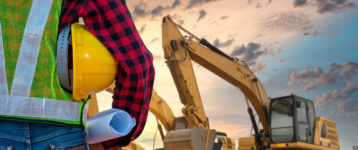 A contractor stands overlooking an excavation site