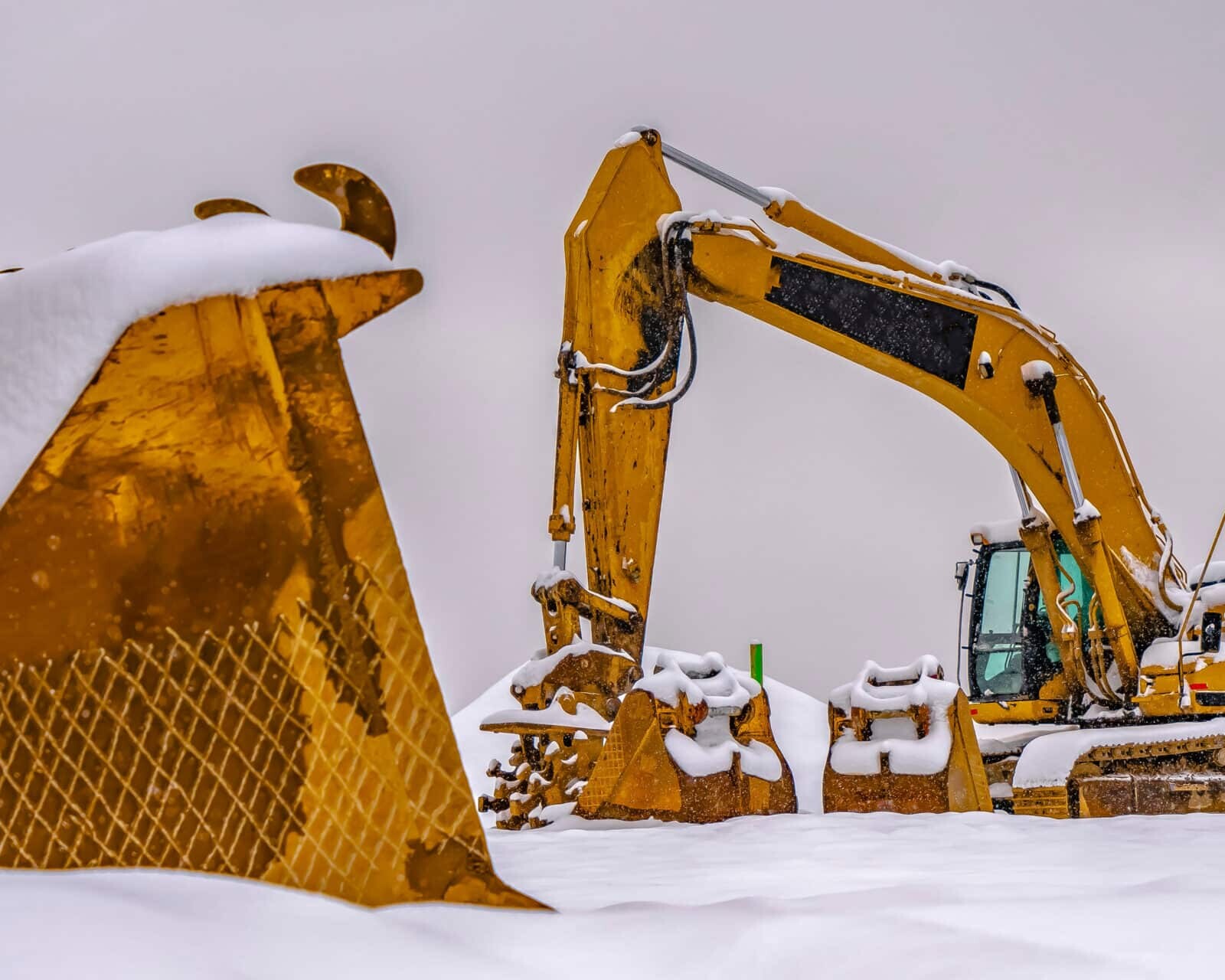 A bright yellow construction vehicles against snow
