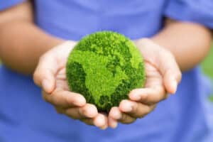 Women hands holding earth on green background.