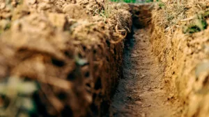 Dig a trench. Earthworks, digging trench. Long earthen trench dug to lay pipe or optical fiber. Construction the sewage and drainage. View from the trench.