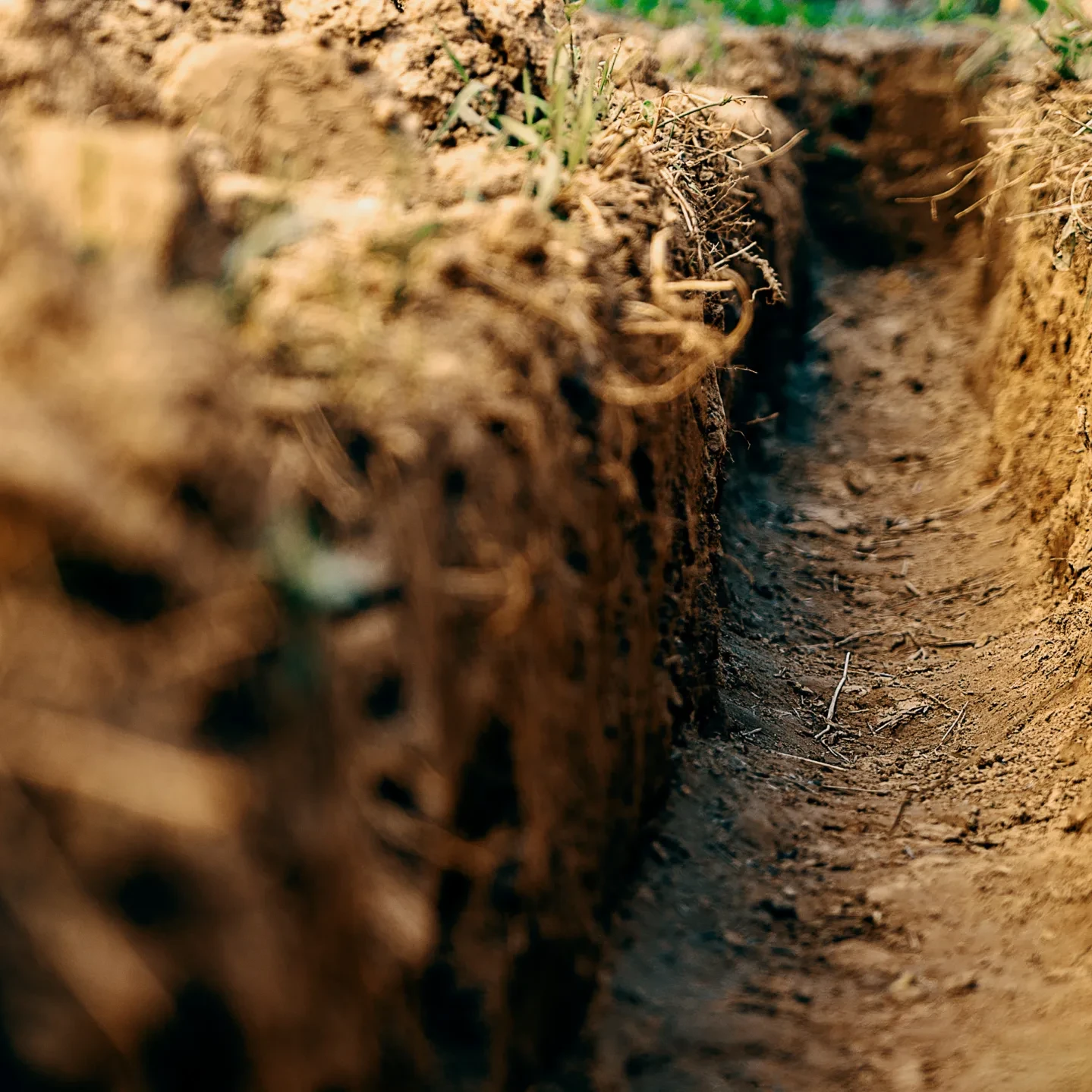 Dig a trench. Earthworks, digging trench. Long earthen trench dug to lay pipe or optical fiber. Construction the sewage and drainage. View from the trench.
