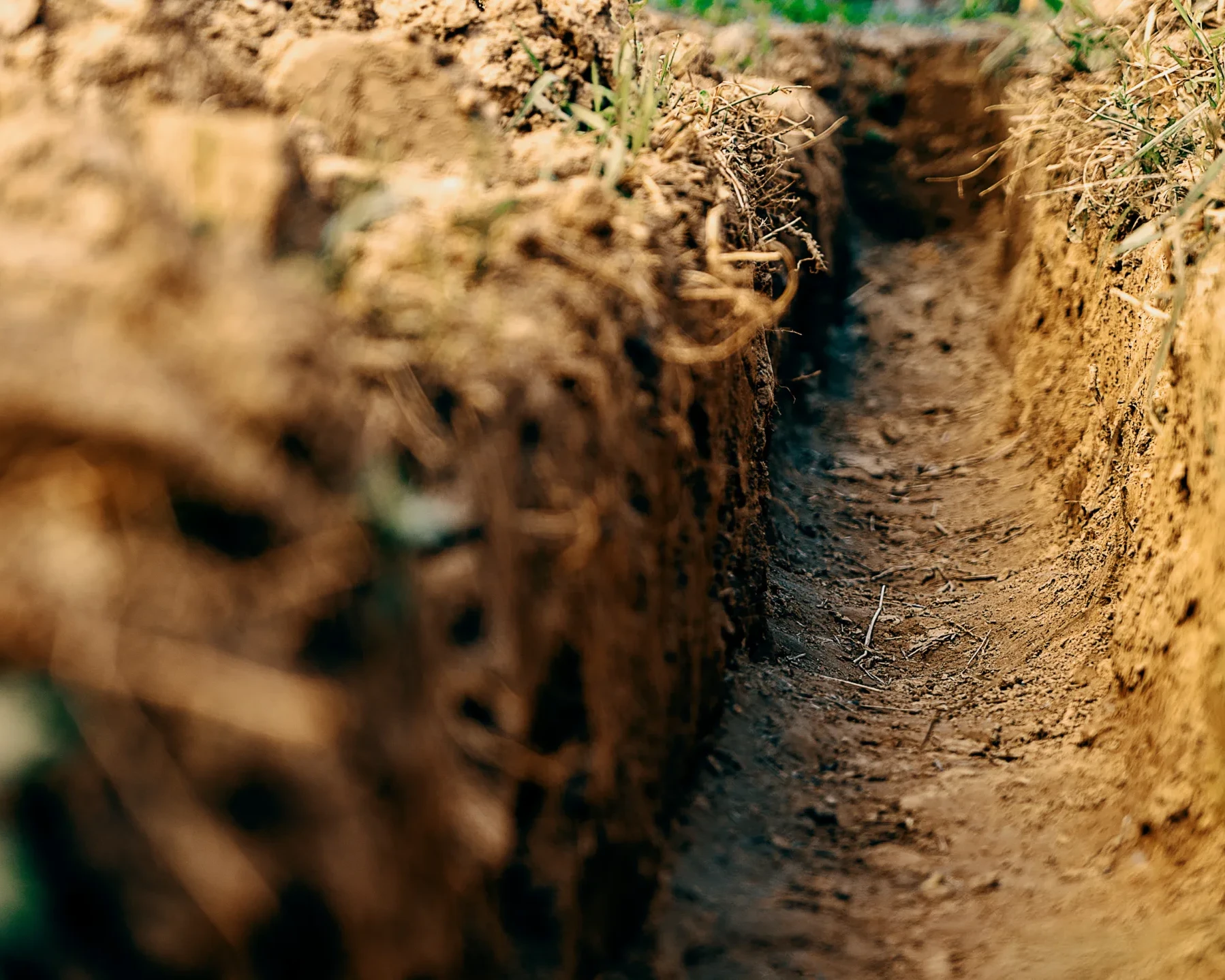 Dig a trench. Earthworks, digging trench. Long earthen trench dug to lay pipe or optical fiber. Construction the sewage and drainage. View from the trench.