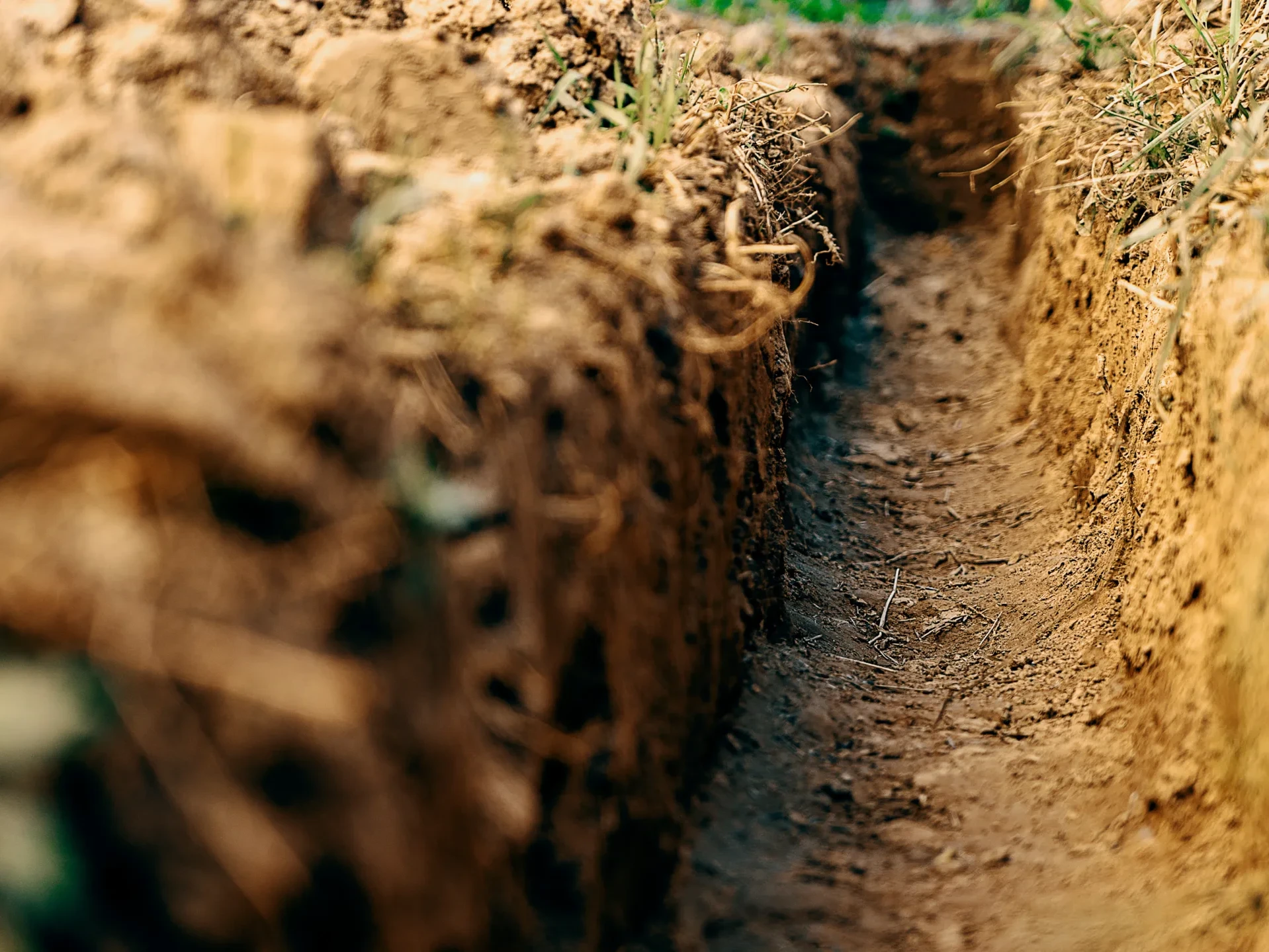 Dig a trench. Earthworks, digging trench. Long earthen trench dug to lay pipe or optical fiber. Construction the sewage and drainage. View from the trench.